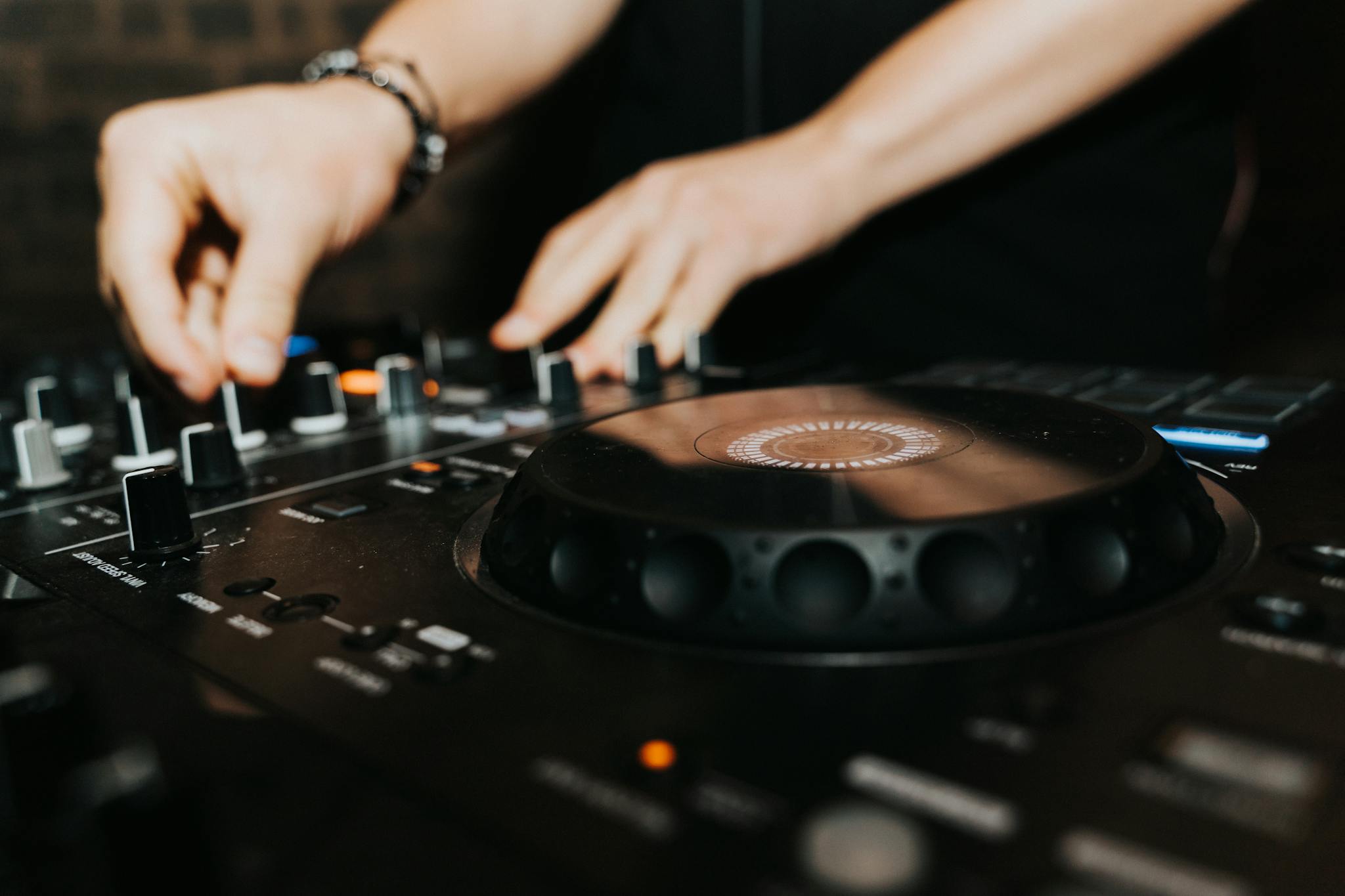 A DJ expertly mixing music on a professional mixer in a club setting, captured in close-up.